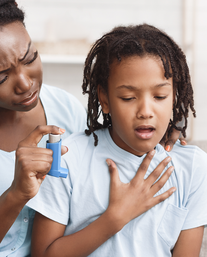 A woman helping a child with his inhaler