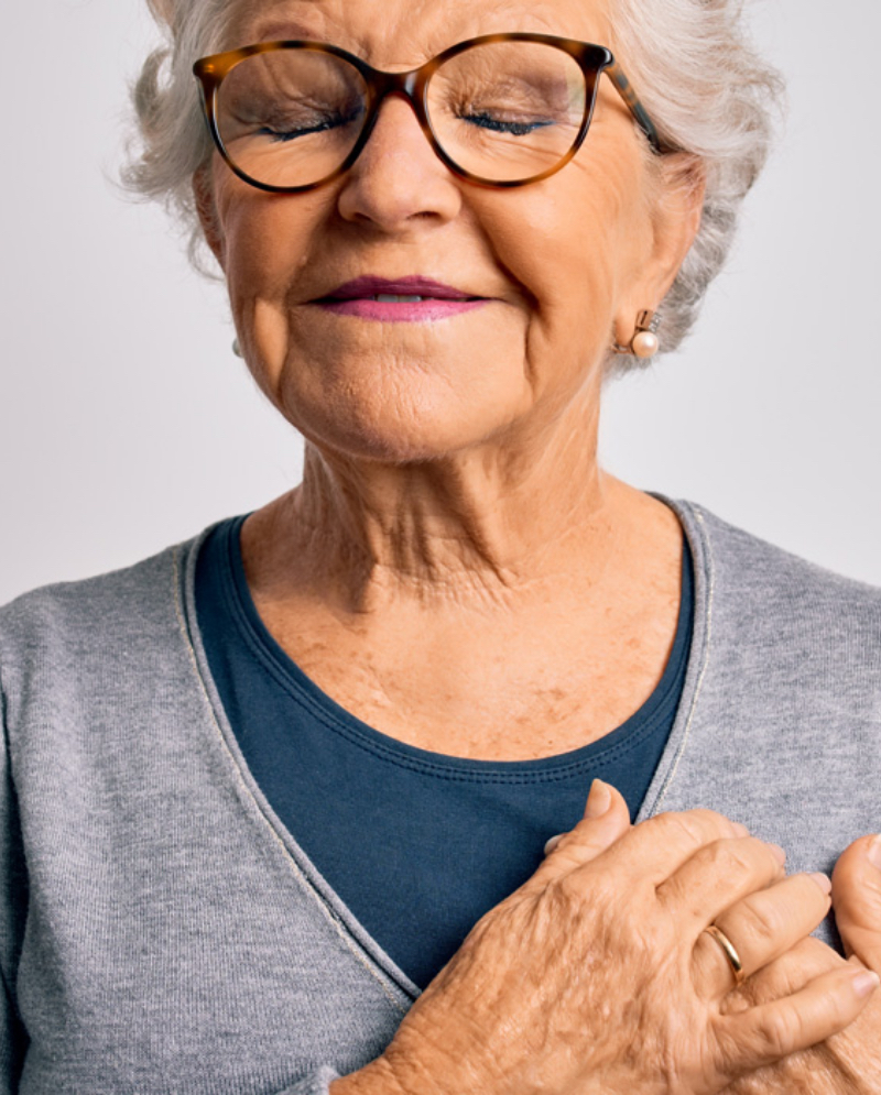 Old woman with glasses gripping her chest