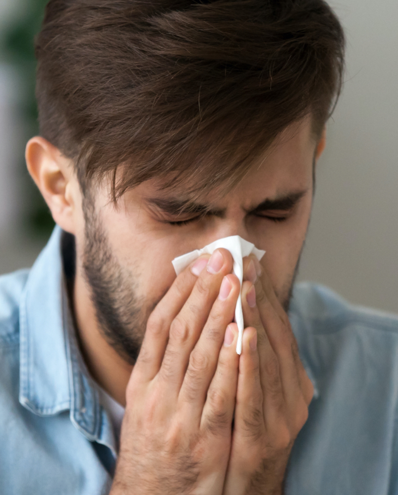 Man blowing his nose into a tissue