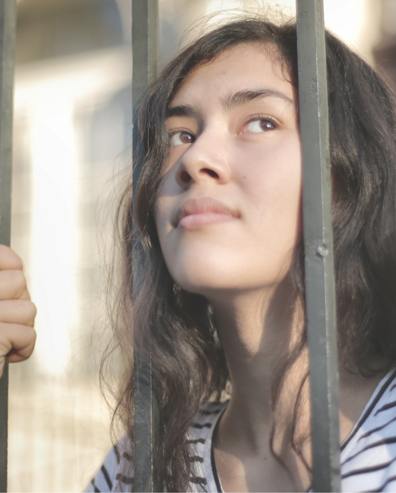 Woman with her face between a set of bars