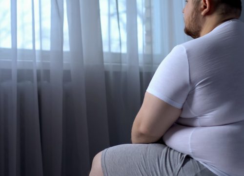 Overweight man sitting on a bed