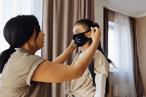 Mom putting a mask on her daughter's face