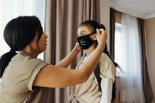 Mom putting a mask on her daughter's face